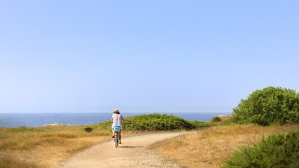 Woman riding bicycle along coastline
