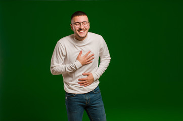young handsome man laughing out loud at some hilarious joke, feeling happy and cheerful, having fun...
