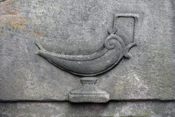 A weathered sandstone relief of an oil-lamp on a cemetery in Potsdam-Germany.