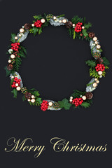 Merry Christmas wreath with winter flora & fauna & gold bauble decorations on dark grey background with copy space. Traditional festive theme with text title.