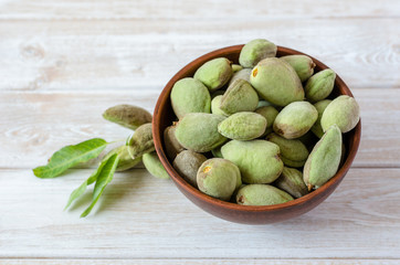 Almonds with green peel in a clay bowl.