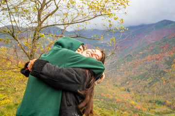 girl and boy in a hug next to the mountain of beeches in autumn