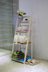 Modern wooden shelf ladder in the bathroom. Bathroom with slippers, white towels and a bathrobe. Design a room for thinking.