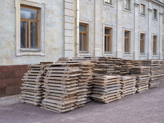 Dismantled scaffolding at the facade of the building. Stack of the wooden elements for building.