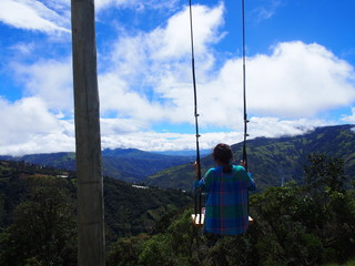 A young woman sitting on a large wooden swing under a beautiful sky, La casa del Arbol (La Casa del Árbol), Banos (Baños), Ecuador