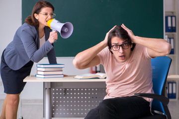 Old female teacher and male student in the classroom