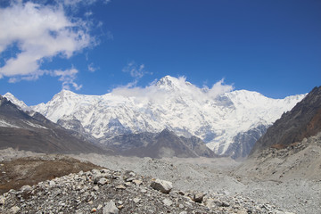 Fototapeta na wymiar Snowy Cho Oyu mountain rises above Ngozumpa glacier covered with stones in Himalayas in Nepal. Route to Everest base camp through Gokyo lakes. Clear blue sky with some clouds.