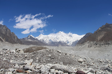 Snowy Cho Oyu mountain rises above Ngozumpa glacier covered with stones in Himalayas in Nepal. Route to Everest base camp through Gokyo lakes. Clear blue sky with some clouds. Whole valley is glacier.