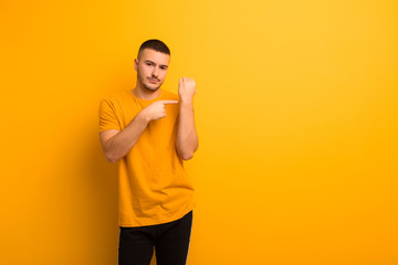 young handsome man looking impatient and angry, pointing at watch, asking for punctuality, wants to...