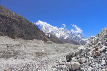 Fototapeta na wymiar View towards summits of Cholatse and Taboche mountains in Himalayas in Sagarmatha national park in Nepal. Mountain peaks rises above Ngozumpa glacier covered with stones. Route to Everest base camp.