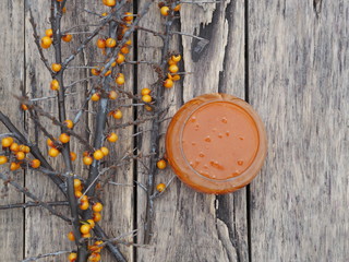 sea ​​buckthorn jam in a glass jar with dry branches on a wooden table