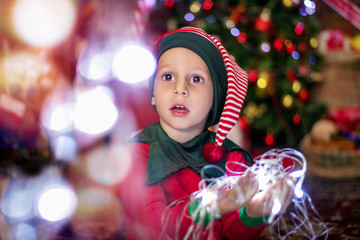 Cute boy indoors near Christmas tree