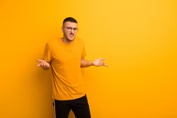 young handsome man feeling clueless and confused, not sure which choice or option to pick,...