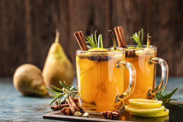 Hot drink cocktail for New Year, Christmas, winter or autumn holidays..Toddy. Mulled pear cider or spiced tea or grog with lemon, pear, cinnamon, anise, cardamom, rosemary. - 305071694