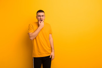 young handsome man with mouth and eyes wide open and hand on chin, feeling unpleasantly shocked,...