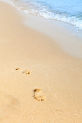 Footprints in the sand on a beach by the sea. Summer vacation concept. blue waves in the background. Relax on the sandy beach. Copy space.