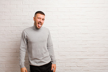 young handsome man with cheerful, carefree, rebellious attitude, joking and sticking tongue out,...