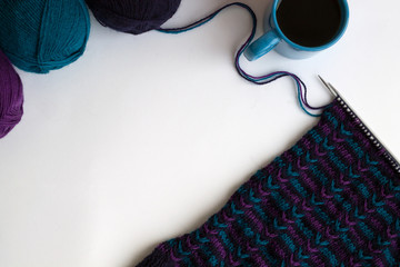 colour balls of wool yarn and knitting with cup of tea or coffee on white background top view with copy space