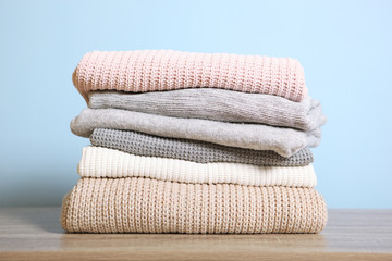 Fototapeta na wymiar a stack of warm sweaters on the table on a colored background.