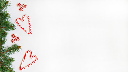 Christmas border made of fir branches, red candy. Christmas wallpaper. Flat lay, top view, copy space.