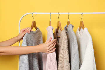 Girl chooses a warm sweater from the wardrobe of the hanger.