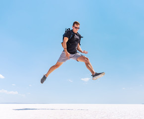 Fototapeta na wymiar Traveling man jumping like a rock star at Tuz salt lake, Turkey. Rock and roll style concept.