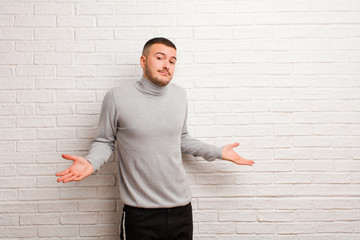 young handsome man feeling puzzled and confused, unsure about the correct answer or decision,...