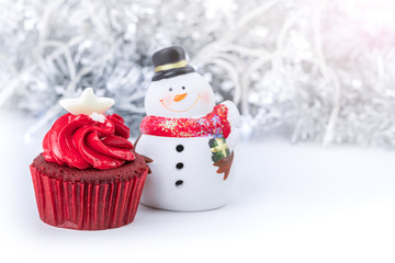 Merry Christmas and Happy New Year with red cupcake and snowman statuette