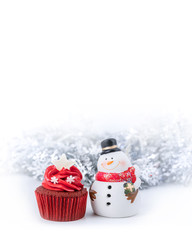 Merry Christmas and Happy New Year with red cupcake and snowman statuette