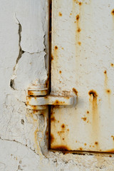 Rusty latch against a rusted white metal wall