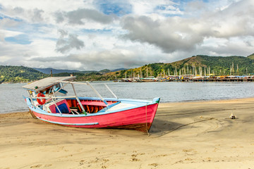 Fototapeta na wymiar Boat on the beach in Paraty Bay, Rio de Janeiro, Brazil, where passenger boats for tourists to be taken to nearby islands or other villages.