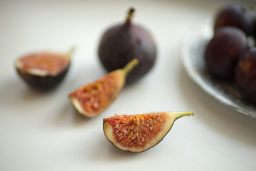 Fig slices and whole figs lie on a white table.
