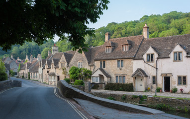 Fototapeta na wymiar CASTLE COMBE, COTSWOLDS, UK - MAY 26, 2018: Street view of old riverside cottages in the picturesque Castle Combe Village, Cotswolds, Wiltshire, England - UK
