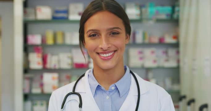 Portrait of an young female pharmacist consultant is smiling in camera in a drug store.