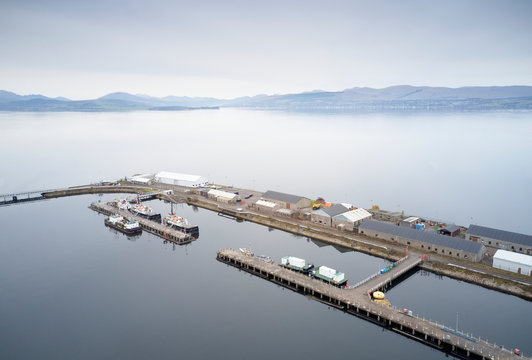 Aerial view of isolated harbour port with ferry ships and grey landscape from above on west coast Scotland near Greenock