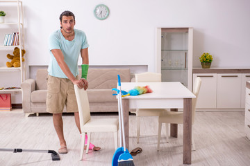 Young injured man cleaning the house