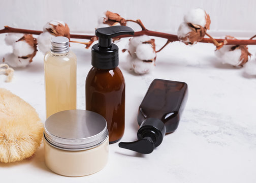 Natural body and hair care cosmetics in glass jars on white table