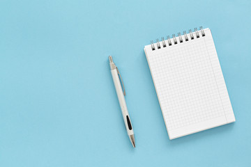 Notebook and pen on blue background. Top view with copy space.