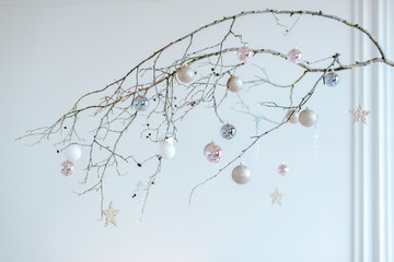 Minimalist wooden stick arrangement with hanging shiny balls and baubles for Christmas home