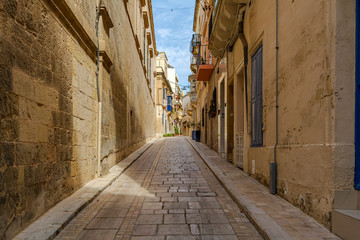 Shady medieval street in Birgu, Malta, near famous Inquisitor's palace. Authentic Maltese urban scene.