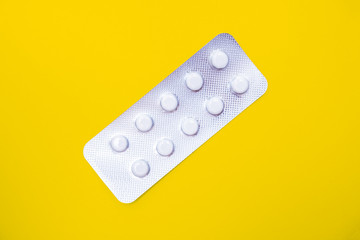 A blister pack of statins, pills tablets for lowering cholesterol on yellow background, prevention and treatment of atherosclerosis and heart disease concept, copy space