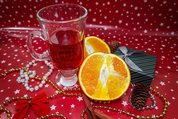 Christmas hot mulled wine with sliced orange, gift box and decor on holiday background