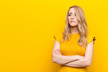 young pretty blonde woman doubting or thinking, biting lip and feeling insecure and nervous,...