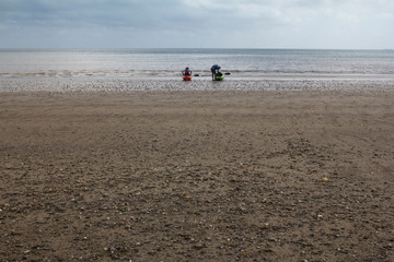 Fototapeta na wymiar Kayakers on a beach in Scotland on a spring morning. 