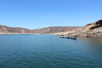 View of the dam El Nihuil in San Rafael, Mendoza, Argentina. Man carrying canoes in the calm waters.
