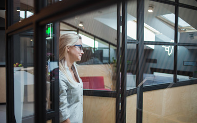 Young confident business woman in glasses on the background of the workspace.