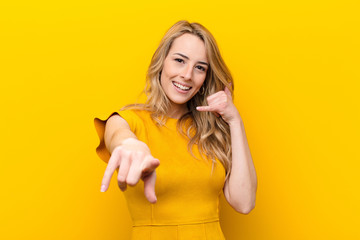 young pretty blonde woman smiling cheerfully and pointing to camera while making a call you later...