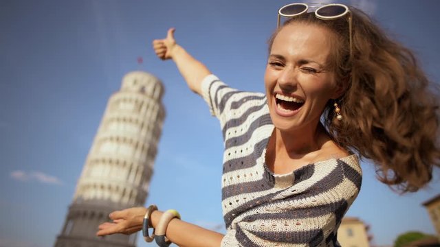 smiling stylish woman in striped blouse posing for travel photos against leaning tower in Pisa, Italy. I&rsquo;m here and I need to take stereotypical tourist photos. having micro trip. сaucasian woman.