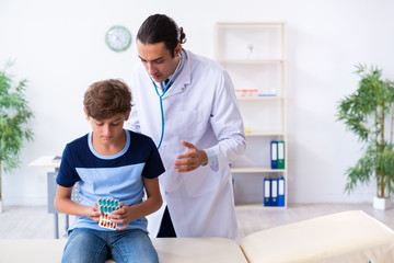 Young male doctor examining boy in the clinic