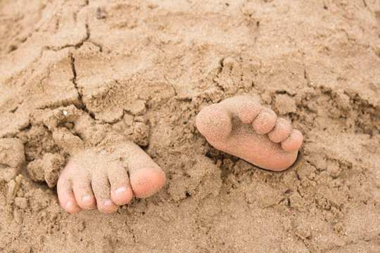 Feet buried in sand on the coast of Scotland on a sunny day. 
